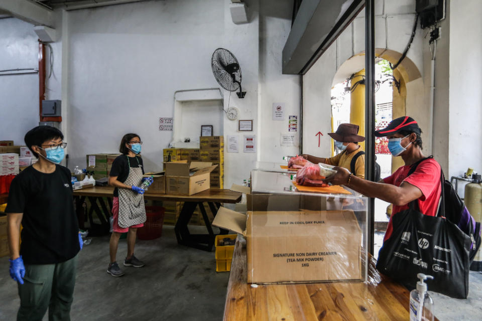 Pit Stop Community Cafe staff observe social distancing guidelines as they serve the homeless one final time in Kuala Lumpur March 30, 2020. — Picture by Firdaus Latif