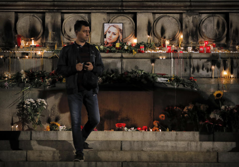 A man walks after lighting candles next to a portrait of slain television reporter Viktoria Marinova after a vigil at the Liberty Monument in Ruse, Bulgaria, Monday, Oct. 8, 2018. Bulgarian police are investigating the rape, beating and slaying of a female television reporter whose body was dumped near the Danube River after she reported on the possible misuse of European Union funds in Bulgaria. (AP Photo/Vadim Ghirda)