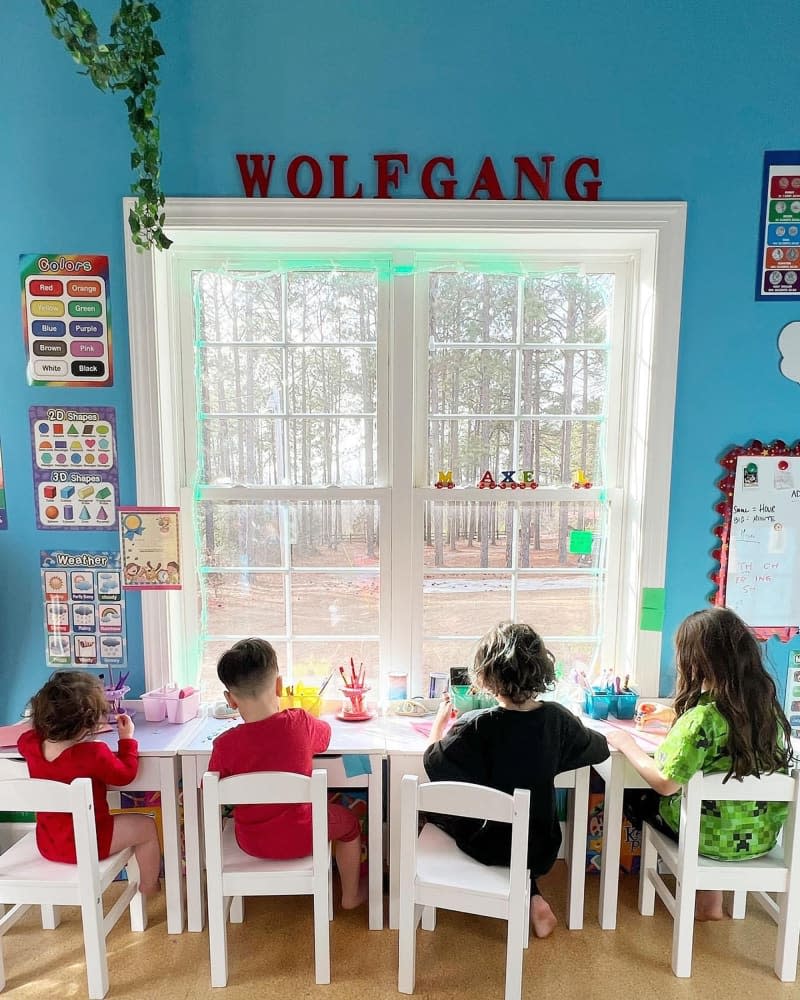 Kids sitting a desks in window.