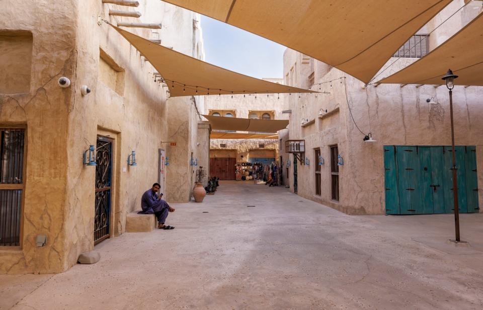 A mostly empty beige alley with beige buildings, pathways, and awnings in Dubai