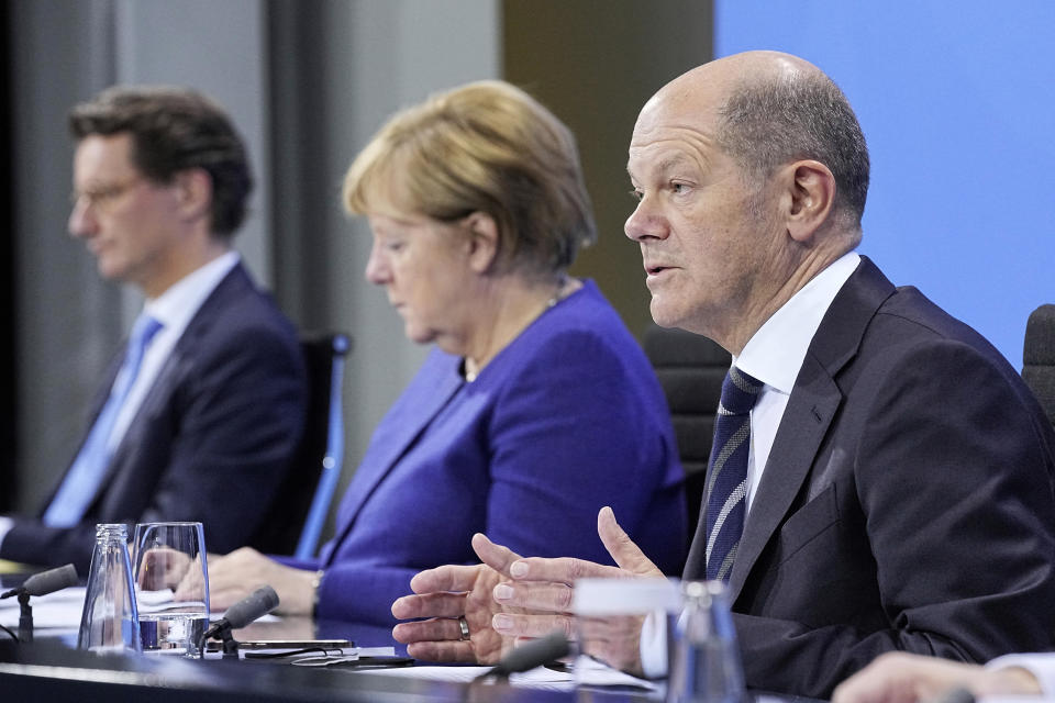 German Chancellor Angela Merkel, left, and Olaf Scholz, Federal Finance Minister, right, meet the media in Berlin, Thursday, Nov. 18, 2021. German lawmakers have approved new measures to rein in record coronavirus infections after the head of Germany’s disease control agency warned the country could face a “really terrible Christmas.” The measures passed in the Bundestag on Thursday includes requirements for employees to prove they are vaccinated, recovered from COVID-19 or have tested negative for the virus in order to access communal workplaces. (Michael Kappeler, Pool via AP)