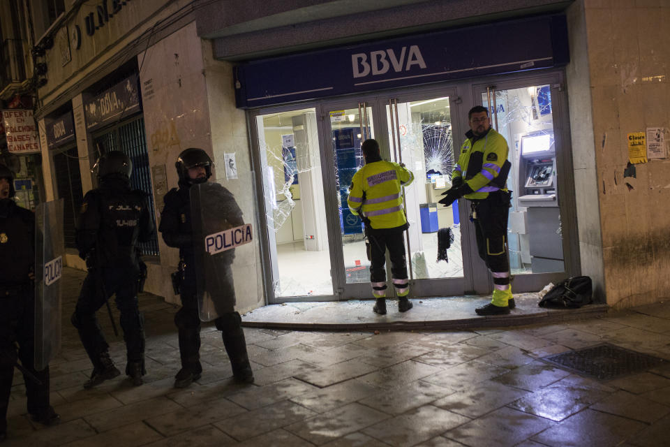 Los agentes acuden a una sucursal bancaria que tiene los cristales rotos tras los disturbios (AP).