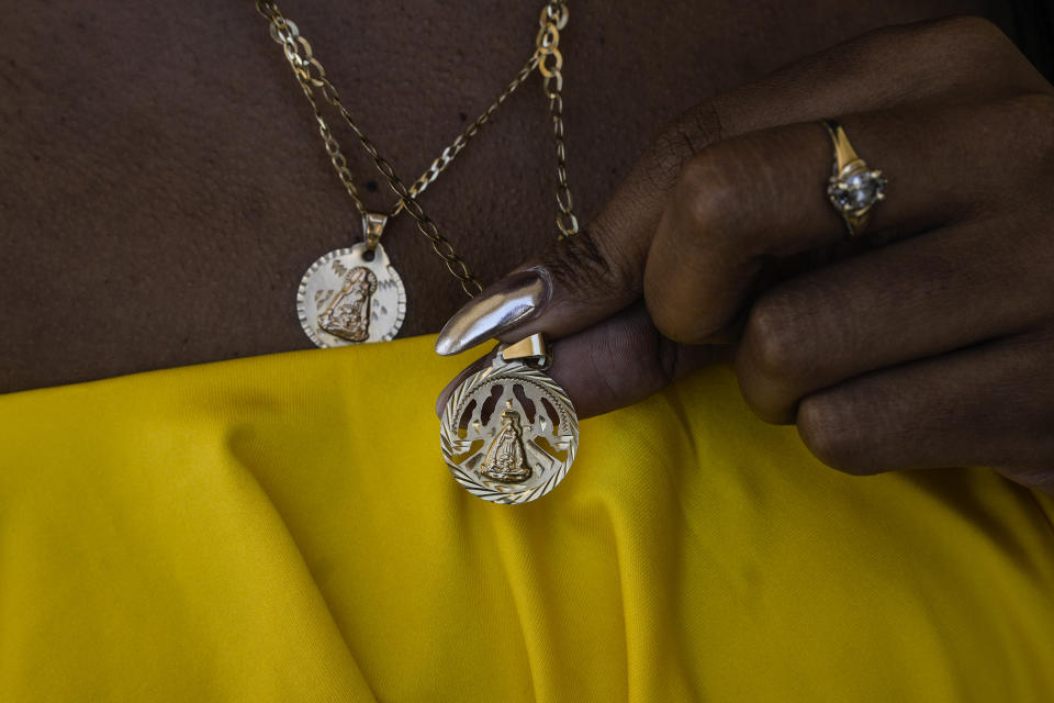 Yaneisy Frometa shows her necklace pendants of the Virgin of Charity of Cobre at the Virgin's shrine in El Cobre, Cuba, Sunday, Feb. 11, 2024. Yamilca said she came to attend Mass at the shrine to fulfill a promise she made to the Cuban patron saint who she attributes to giving her a healthy baby. (AP Photo/Ramon Espinosa)