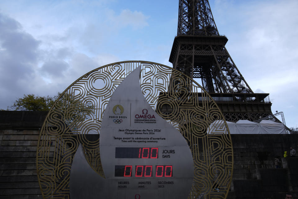 FILE - The countdown clock reading 100 days before the Paris 2024 Olympic Games opening ceremony is seen April 17, 2024 in Paris. The Paris Olympics involve about 10,500 athletes from 200 countries or regions. But the Olympics are more than just fun and games. They are a giant business that generates billions of dollars in income for the International Olympic Committee. (AP Photo/Christophe Ena, File)