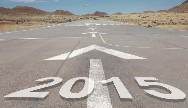 Date numbers 2015 hovering on airport runway with direction markings and mountains in the background