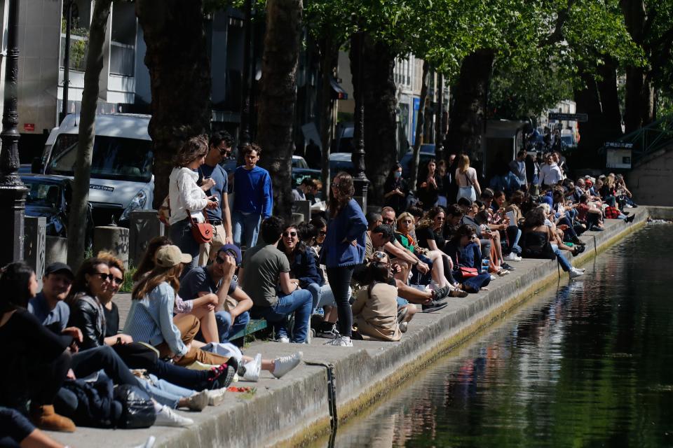 People sit on a bank of the Canal Saint-Martin in Paris, on May 16, 2020, on the first weekend after France eased lockdown measures. (Photo: FRANCOIS GUILLOT via Getty Images)