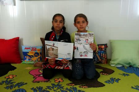 Iraqi refugees pose with their art therapy drawings and renditions by U.S. photographer Brian McCarty at Debaga camp for the displaced on the outskirts of Erbil, Iraq July 8, 2018. REUTERS/Azad Lashkari