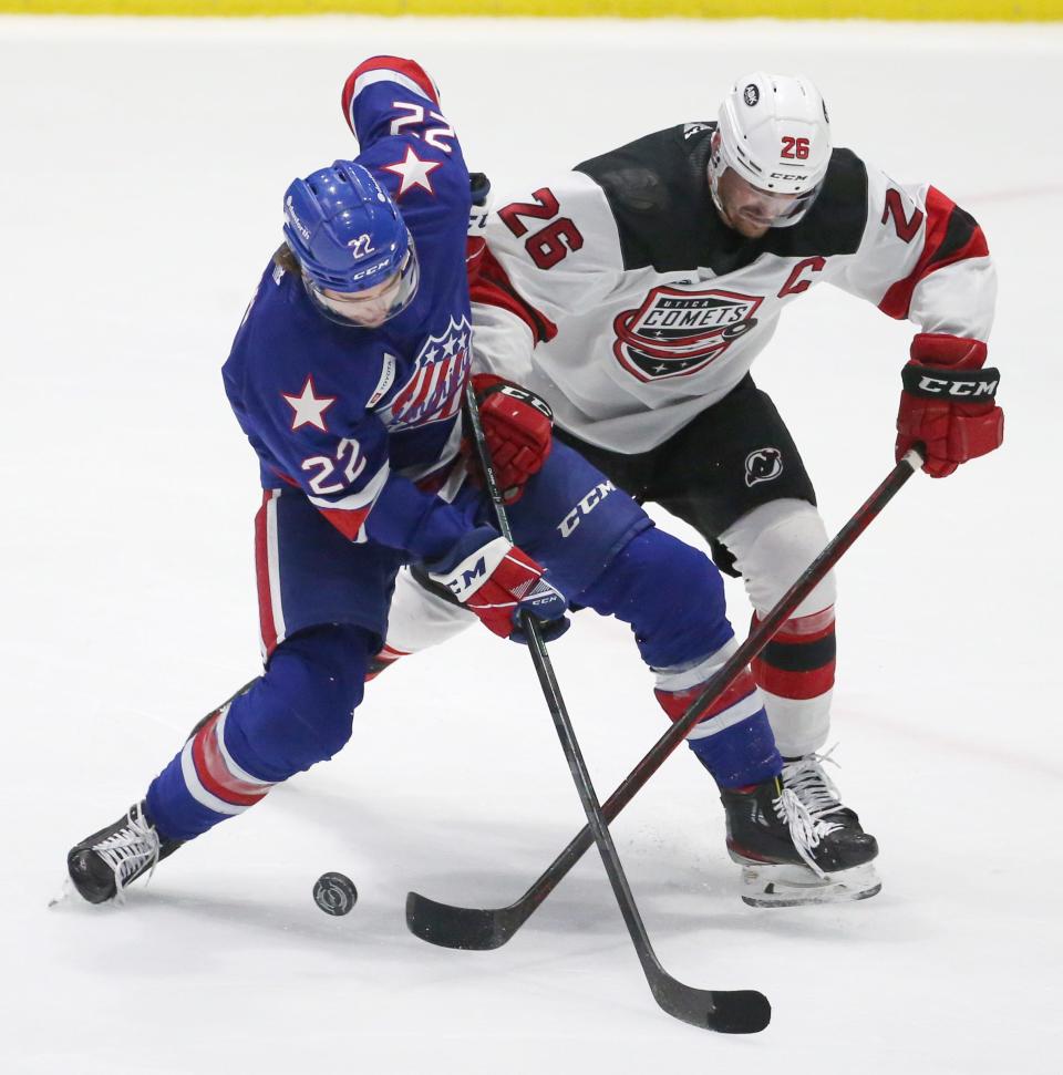 Rochester's Jack Quinn (22), left, has the puck poked away by Utica's Ryan Schmelzer (26), right, as he goes to take a shot on goal during Game 4 of their North Division semifinal series Tuesday, May 17, 2022 at Blue Cross Arena.  Utica won the game 4-2.