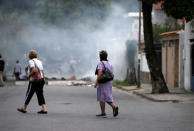 Unas mujeres pasan detrás de una barricada montada en Caracas por opositores al Gobierno de Nicolás Maduro en Venezuela, abr 20, 2017. Por segundo día consecutivo, miles de partidarios de la oposición salieron el jueves a las calles de Venezuela para protestar en contra del presidente Nicolás Maduro, a quien acusan de la grave crisis económica y de haber desvirtuado su Gobierno al convertirlo en una dictadura. REUTERS/Carlos Garcia Rawlins