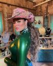 <p>Wearing a pink bejeweled cowboy hat, green latex bodysuit, and "K" chandelier earrings, the singer makes her own fashion rules. </p>