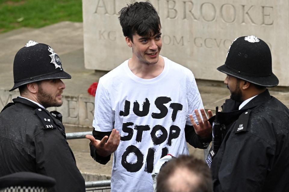 A protester from climate protest group 'Just Stop Oil' is apprehended by police officers close to where Britain's King Charles III and Britain's Camilla, Queen Consort will be crowned at Westminster Abbey in central London on May 6, 2023. - The set-piece coronation is the first in Britain in 70 years, and only the second in history to be televised. Charles will be the 40th reigning monarch to be crowned at the central London church since King William I in 1066. (Photo by LOIC VENANCE / AFP) (Photo by LOIC VENANCE/AFP via Getty Images)