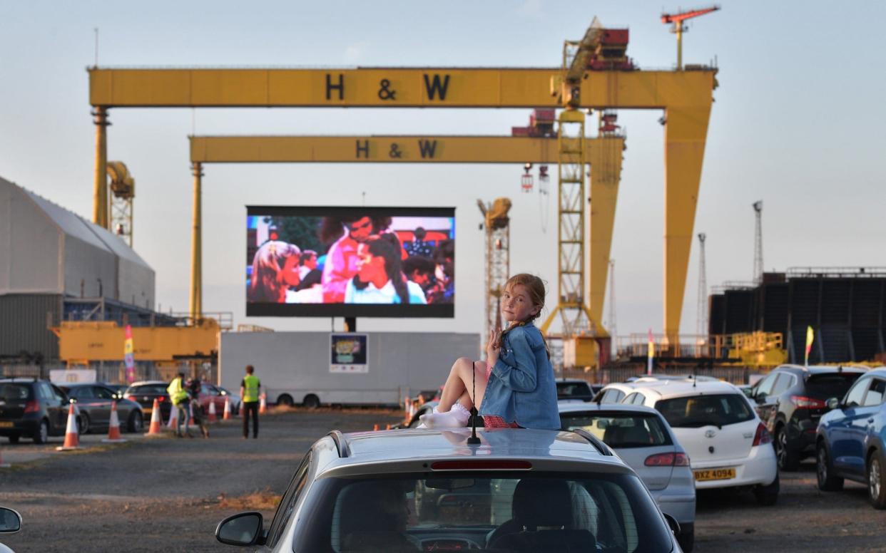 Bridget Nolan watches Grease on the big screen from the roof of her mothers car in the Titanic Quarter beneath the famous Harland and Wolff cranes on June 13, 2020 in Belfast, Northern Ireland. The drive-in cinema is the first of its kind taking place in the UK as some of the restrictions surrounding the Covid-19 pandemic are relaxed. - Getty Images