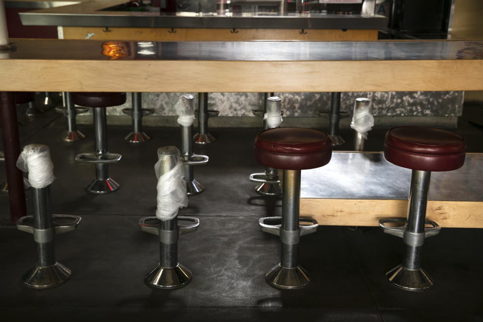 Banquetas, algunas sin asiento para obligar a mantener la distancia social, en un bar cerrado temporalmente por la pandemia del coronavirus, en Los Ángeles, el 8 de julio de 2020. (AP Foto/Jae C. Hong)