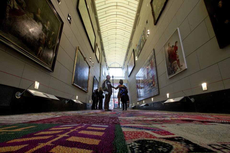 This March 19, 2013 photo shows visitors in the civic guard gallery of the Amsterdam Museum, Netherlands. If you don't manage to get into the Rijksmuseum to see Rembrandt's Night Watch, right around the corner from the Begijnhof is another hidden and free gem of the city, the Schuttersgalerij, or Civil Guard Gallery, of the Amsterdam Museum. This short covered passageway is home to, among other things, a handful of much smaller portraits of civil guards similar in style, if not size, to Rembrandt's famous work. (AP Photo/Peter Dejong)