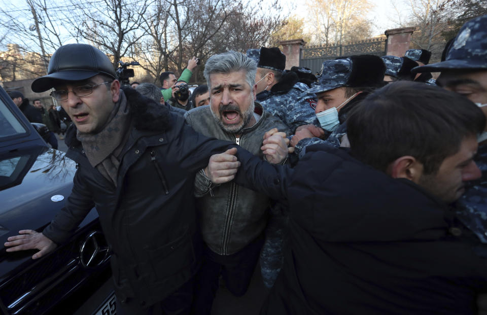 Opposition demonstrators try to break through a police line during a rally to pressure Armenian Prime Minister Nikol Pashinyan to resign in Yerevan, Armenia, Tuesday, March 9, 2021. Thousands of opposition supporters blockaded the Armenian parliament building and engaged in occasional scuffles with police on Tuesday to press a demand for the country's prime minister to step down. (Stepan Poghosyan/PHOTOLURE via AP)