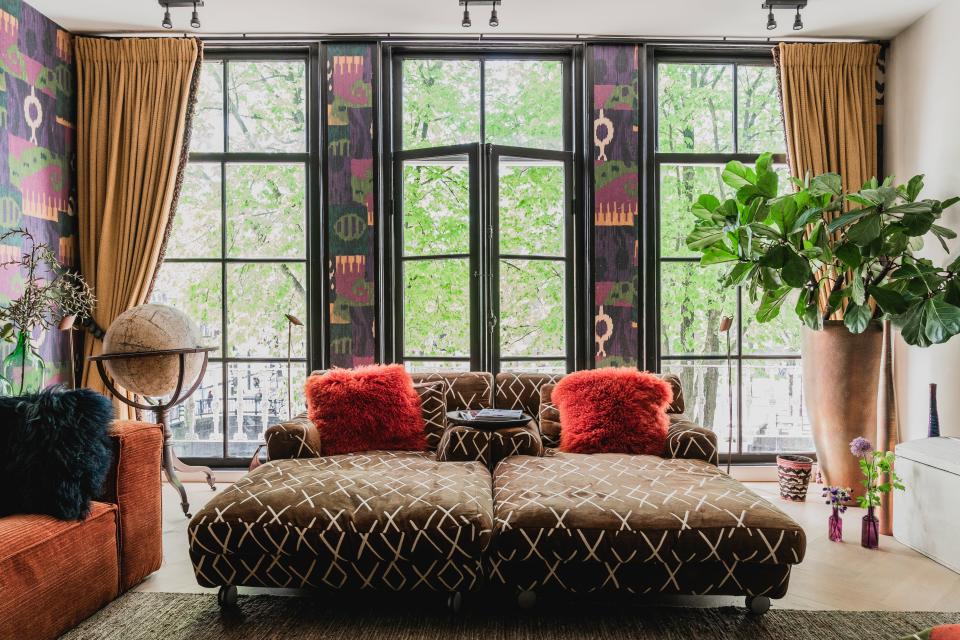 The orange corduroy couch is from Bolia, which sits atop a Hemp carpet from Loook. The antique globe was found by her husband. Two chaise longues upholstered in a Le Manach fabric sit side-by-side.