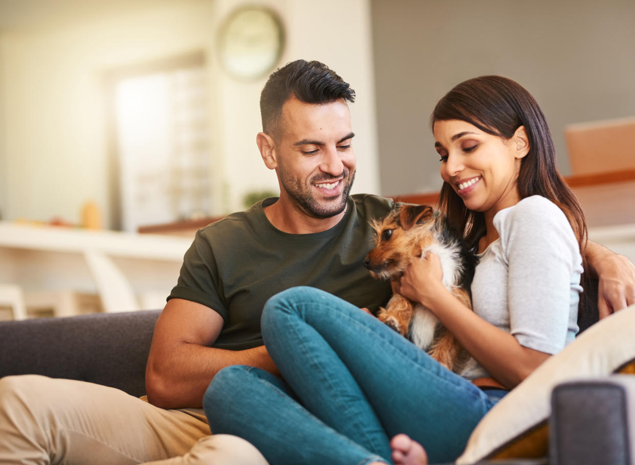 Shot of an affectionate young couple relaxing with their pet dog at home