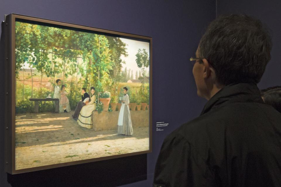 A visitors looks at the painting ''After Lunch" (La Pergola),1868, by Silvestro Lega, at the Orangerie Museum in Paris, Tuesday April 9, 2013. A new exhibit at Paris’ Orangery museum called “The Macchiaioli: the Italian Impressionists?” explores how a Florence-based art movement that predated French impressionism by a decade was already using the themes of light, the outdoors and spontaneity that’s more associated with the likes of Monet or Renoir. (AP Photo/Jacques Brinon)