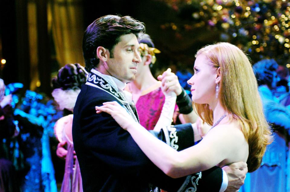 Patrick Dempsey and Amy Adams dressed in formal attire, dancing in a ballroom filled with other dancers in the background