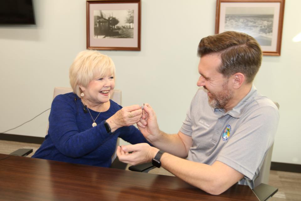 Linda York hands her house key to Commissioner Josh Street on Thursday after she sold her home to Panama City as part of the Rebuild Florida Voluntary Buyout Program.