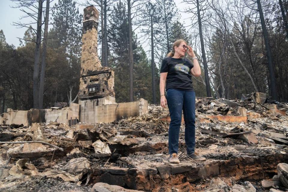 Linda Fischer stands near the chimney of her home, burned in the Park Fire, in Forest Ranch on Wednesday. Fischer and her husband, who have been together for 15 years, got married on the deck of their house.