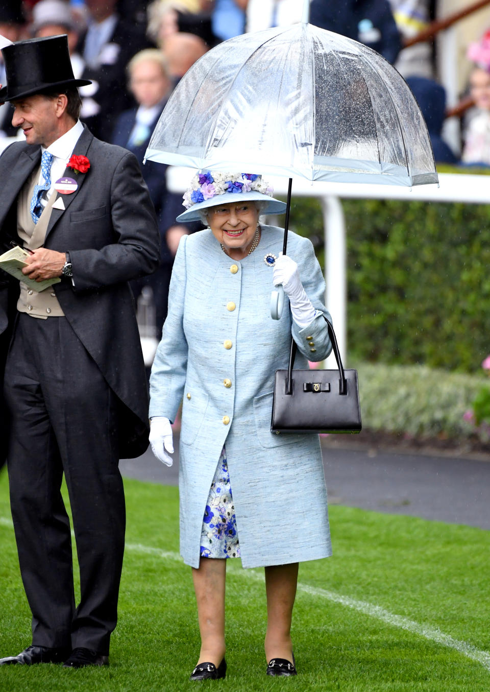 The Queen braved the rain in a mottled duck egg coat and floral dress by Stewart Parvin with a matching floral-adorned hat by milliner Rachel Trevor Morgan.<em> [Photo: PA]</em>