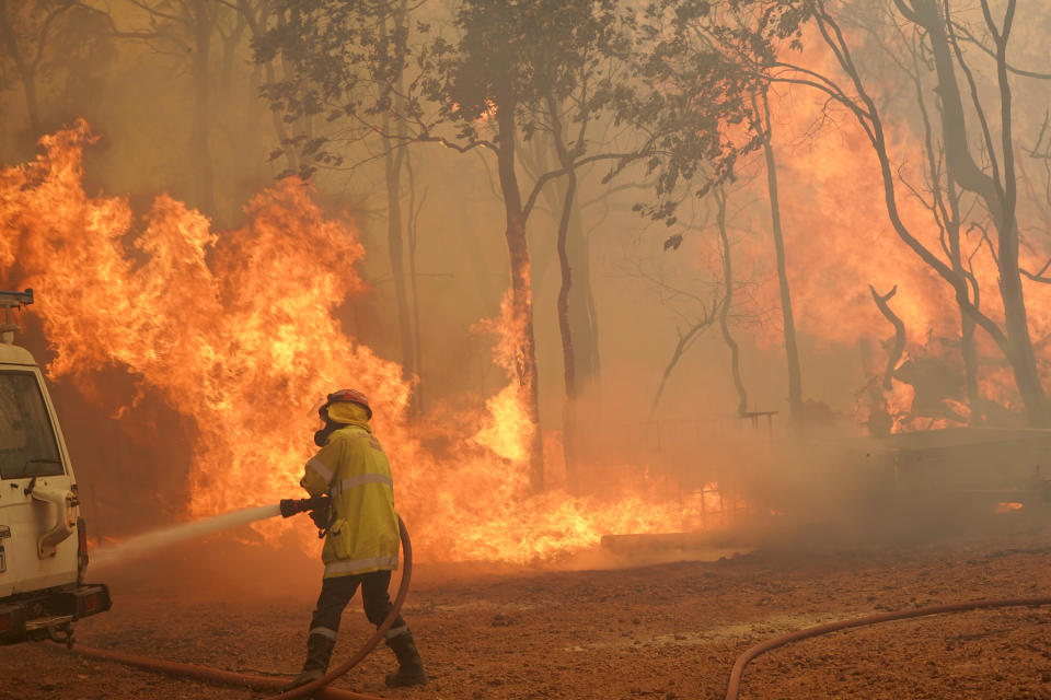 In this photo provided by Department of Fire and Emergency Services, a firefighter attends to a fire near Wooroloo, northeast of Perth, Australia, Tuesday, Feb. 2, 2021. An out-of-control wildfire burning northeast of the Australian west coast city of Perth has destroyed dozens of homes and was threatening more. (Evan Collis/DFES via AP)