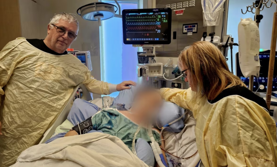 Heather Insley and her husband Bill stand by the bed of a patient they believed to be their 43-year-old son Sean Cox. (Submitted by Heather Insley)