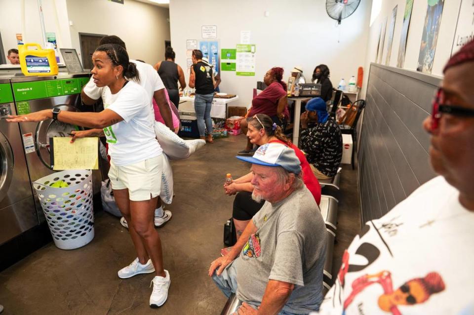 Leah McPherson, left, directs customers to washing machines at last month’s Community Laundry Day at Leah’s Laundromat on the Q in Kansas City, Kansas. “There was no way we were going to change this area around without injecting a lot of hope, a lot of stuff that people need in the community,” Leah’s husband John McPherson said.