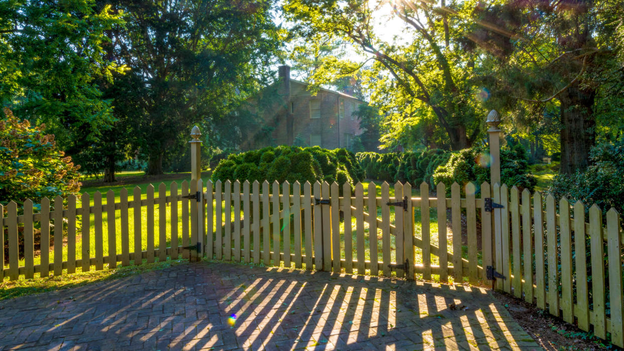 Small town neighborhood with trees and fence surrounding house - Image.