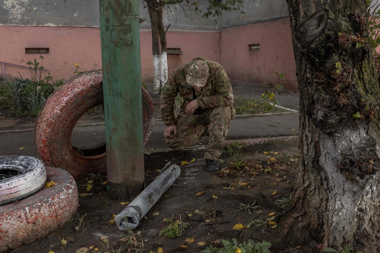 A man in a military uniform looks at a part of a missile next to a residential building that was damaged during an overnight Russian attack, in the southern city of Kherson, on Oct. 30, 2023, amid the Russian invasion of Ukraine.