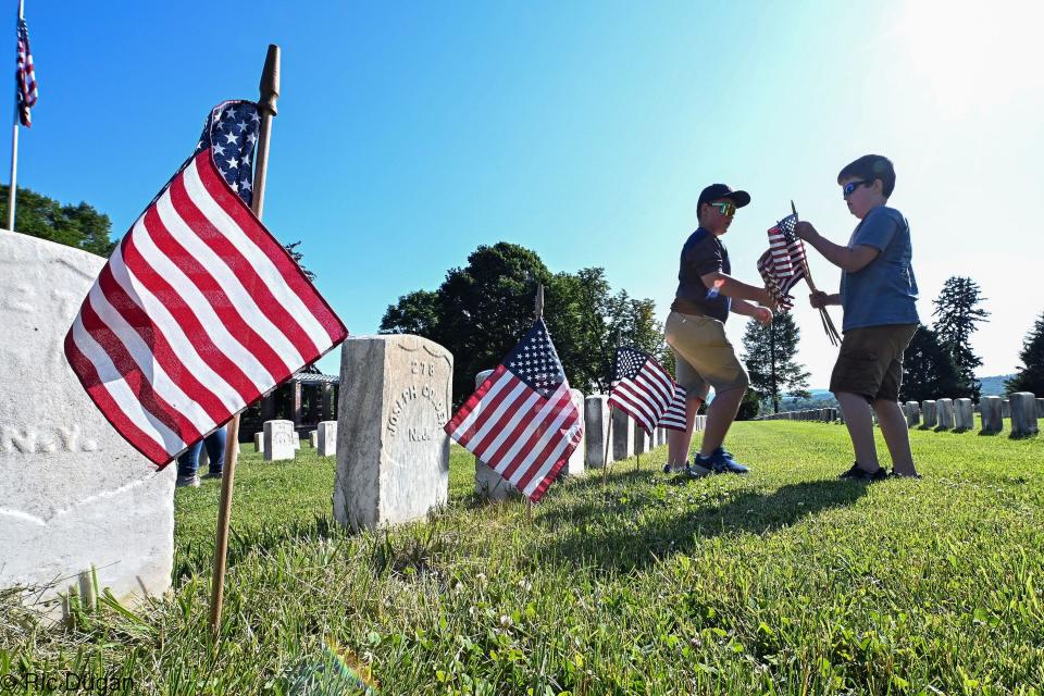 Tanner Harrell, left, and Ryder Harshaw prepare to place American flags at the gravestones in Antietam National Cemetery on Thursday. The tradition is for fifth graders from the school to place nearly 5,000 of the flags at the stones to commemorate Memorial Day.