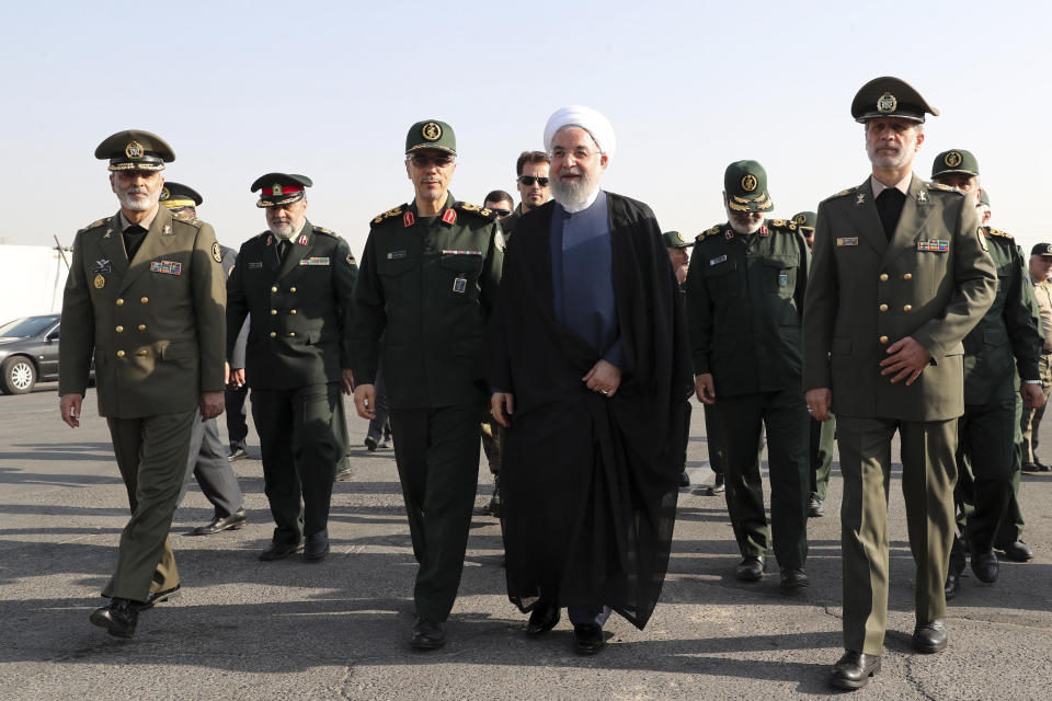 In this photo released by the official website of the office of the Iranian Presidency, President Hassan Rouhani, center, arrives for a military parade ceremony marking 39th anniversary of outset of Iran-Iraq war, as he is accompanied by commanders of armed forces in front of the shrine of the late revolutionary founder Ayatollah Khomeini, just outside Tehran, Iran, Sunday, Sept. 22, 2019. (Iranian Presidency Office via AP)