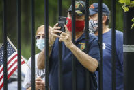 A motorcade of veterans stand on the sidewalk outside the VA Medical Center as wreaths are lain beside memorial stones on the premises, Monday, May 25, 2020, in the Brooklyn borough of New York. (AP Photo/John Minchillo)