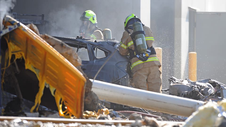 Fire crew at the scene where a light plane crashed into the back of a DFO building at Essendon airport. Source: AAP