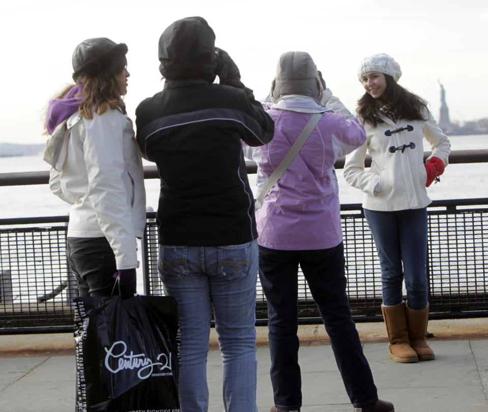 FILE - In this Jan. 4, 2012 file photo, Brazilian tourists take pictures of each other in front of the Statue of Liberty in New York. The Statue of Liberty, which has been closed to visitors since Superstorm Sandy, is scheduled to reopen for tours July Fourth, when Statue Cruises resumes departures for Liberty Island from Lower Manhattan. But for tourists who want a photo of the famous statue without visiting the island, there are many options, including a variety of vantage points around the Lower Manhattan waterfront. (AP Photo/Seth Wenig, file)