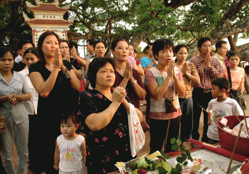 FILE - This Aug. 23, 2002 file photo shows Vietnamese women and children praying at the Tay Ho pagoda in Hanoi, Vietnam. Hanoi is packed with beautiful Buddhist temples, many of them ancient. Just follow the scent of burning incense and step away from the chaotic streets to take a moment to reflect and soak in the calm. The One Pillar Pagoda is among the city's most famous sites, but many Vietnamese flock to the Tay Ho Pagoda overlooking the city's large West Lake to leave offerings and pray, especially on auspicious days. (AP Photo/Richard Vogel, file)