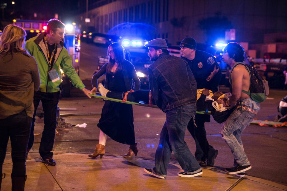 Bystanders assist first responders at the scene at SXSW festival in Austin, TX early Thursday morning March 13, 2014 where 2 people died and dozens more were injured after a hit and run. Police say a man and woman have been killed after a drunken driver fleeing from arrest crashed through barricades set up for the South By Southwest festival and struck the pair and others on a crowded street. (AP Photo/Colin Kerrigan)