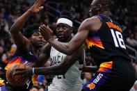 Milwaukee Bucks' Jrue Holiday drives between Phoenix Suns' Bismack Biyombo and Aaron Holiday during the first half of an NBA basketball game Sunday, March 6, 2022, in Milwaukee . (AP Photo/Morry Gash)