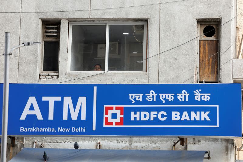 FILE PHOTO: A man looks out of a window next to the signboard of HDFC Bank's automated teller machine (ATM) in New Delhi