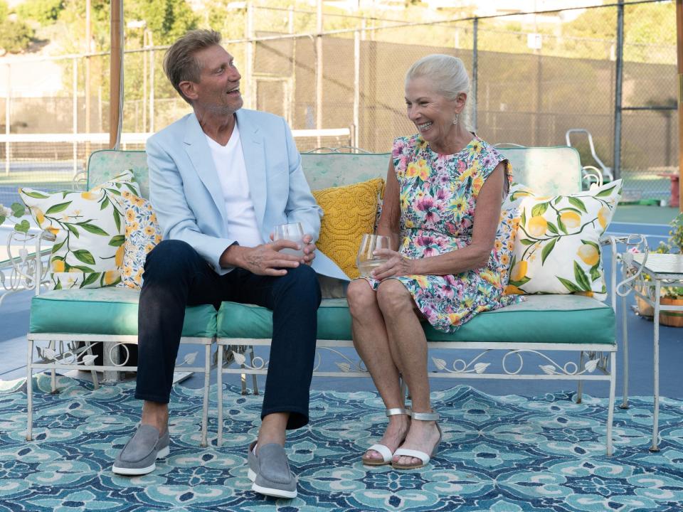 Gerry and Ellen sit next to each other on a bench in the midst of a pickleball court on "The Golden Bachelor."