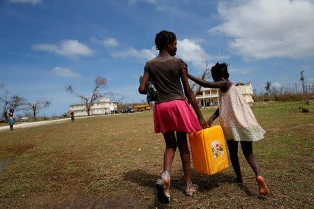 Children carry a plastic container filled with water in a damaged orphanage after Hurricane Matthew passes Jeremie, Haiti, October 11, 2016. REUTERS/Carlos Garcia Rawlins