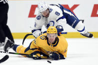 Tampa Bay Lightning center Tyler Johnson (9) falls onto Nashville Predators left wing Erik Haula (56) as they chased the puck during the first period of an NHL hockey game Tuesday, April 13, 2021, in Nashville, Tenn. (AP Photo/Mark Zaleski)