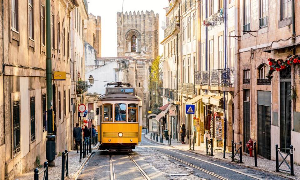 Straat in de oude stad van Lissabon met gele tram en de kathedraal van Lissabon op de achtergrond.  Lissabon, Portugal