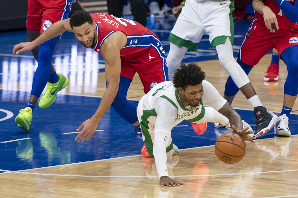 Boston Celtics' Marcus Smart, right, dives for the ball with Philadelphia 76ers' Ben Simmons, left, during the first half of an NBA basketball game, Friday, Jan. 22, 2021, in Philadelphia. (AP Photo/Chris Szagola)