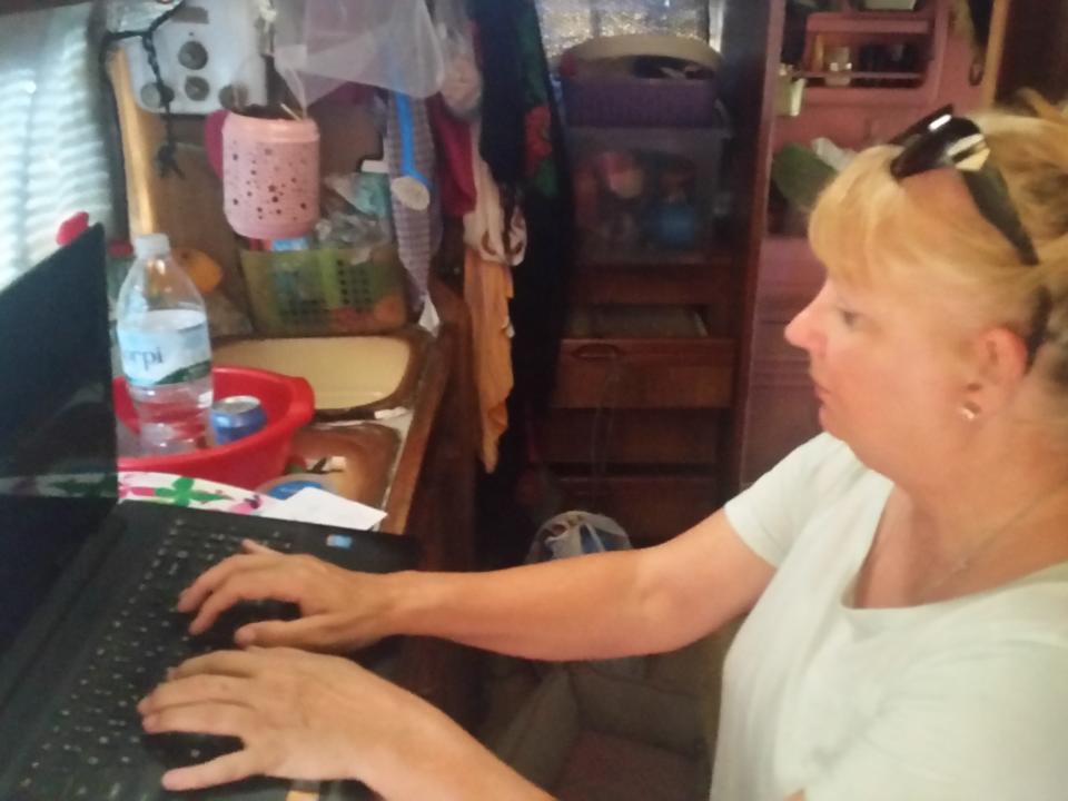 A woman sitting at her laptop and typing in a small space.