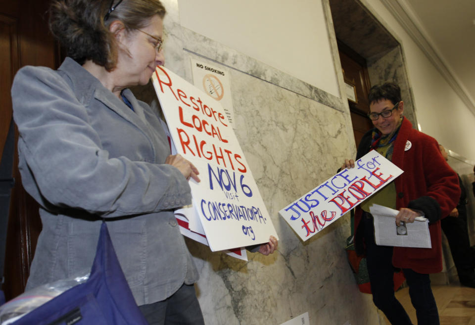 Cynthis Walter, left, with the Westmoreland Marcellus Citizens Group holds her sign with another woman after they left the Pennsylvania state Supreme Courtroom in Pittsburgh where the court was hearing arguments from seven municipalities challenging portions of a new law that regulates natural gas exploration on Wednesday, Oct. 17, 2012. (AP Photo/Keith Srakocic)