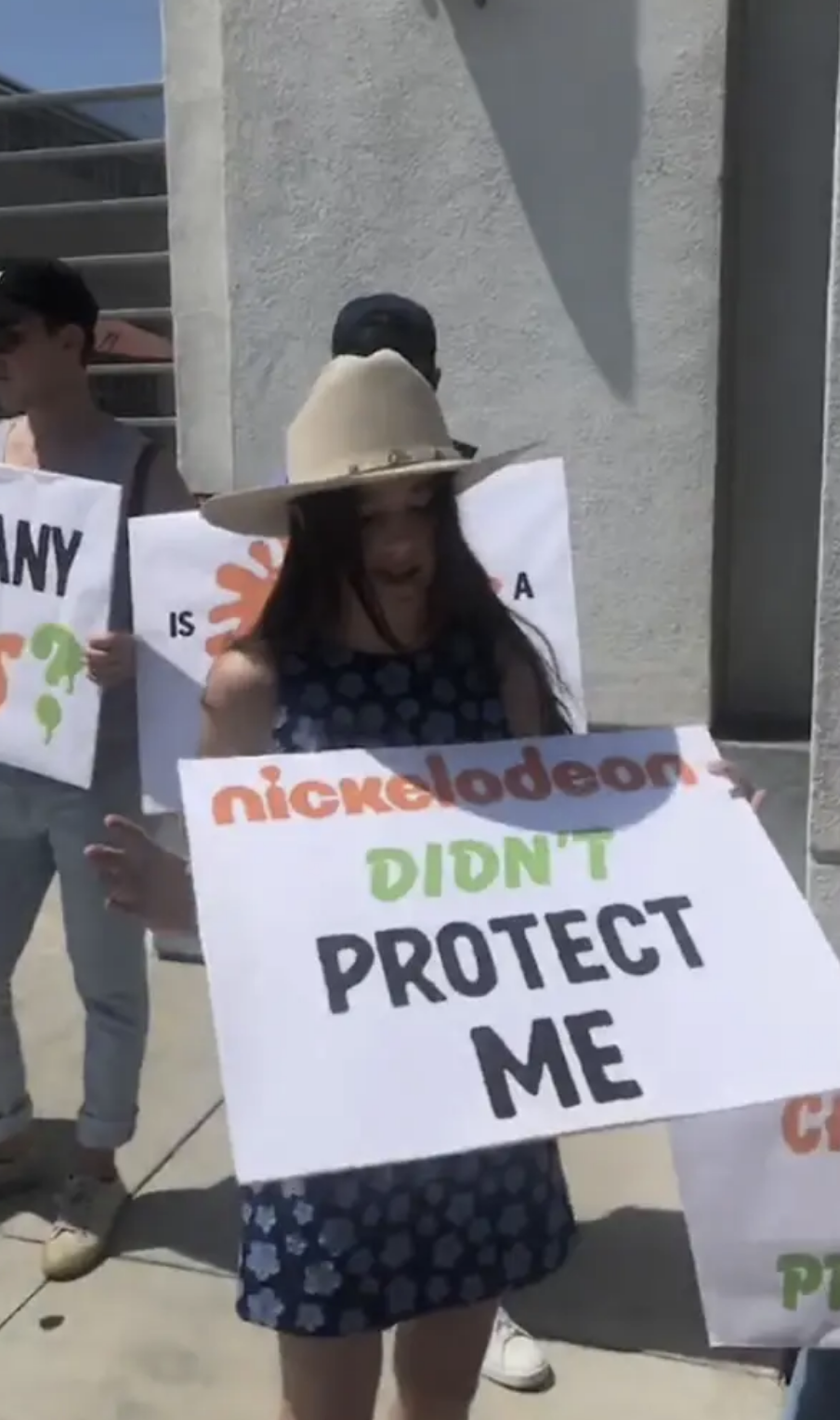 Alexa holding a sign that says "Nickelodeon didn't protect me"