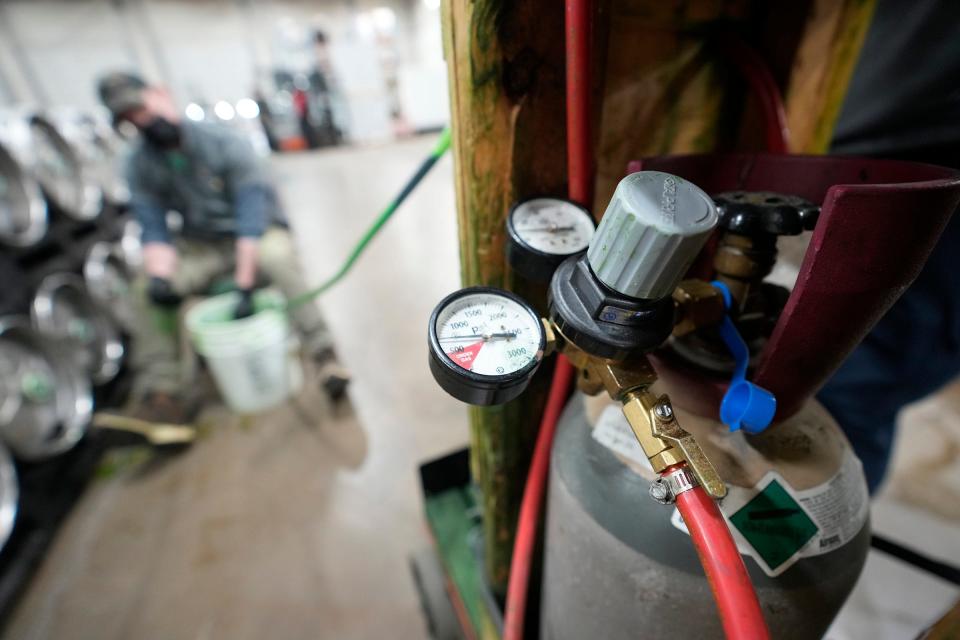 A CO2 device is used to add green food coloring as Beer Capitol Draft sales-service department manager Ryan Mallery feeds the coloring through a beer line into a keg on March 6.