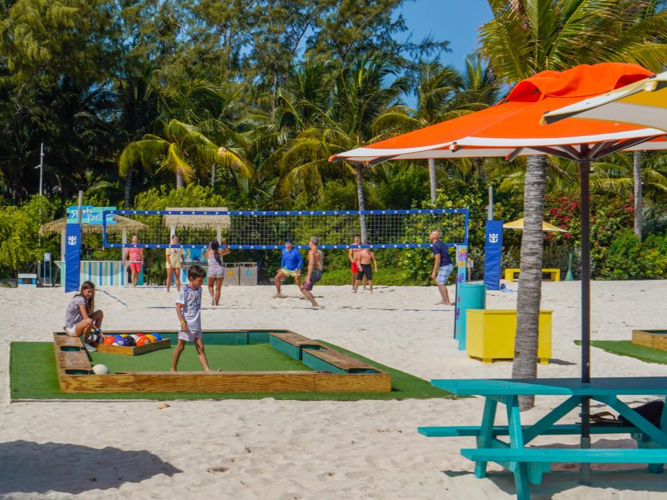 People play life-size pool and volleyball at CocoCay with palm trees in the background